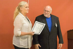 Jackie Travis, Avivo's Mobility Mentor, hands Dan his certificate of perfect attendance at his graduation ceremony.