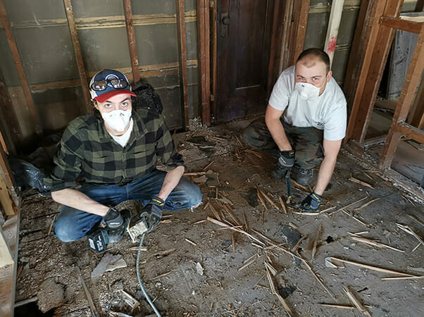 Two contractors from Plekkenpol Builders, Inc. assess the floor of one of Avivo's family recovery housing units in the early stages of renovations.