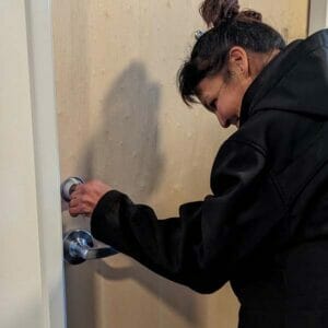 Woman who just obtained housing opens her apartment door.