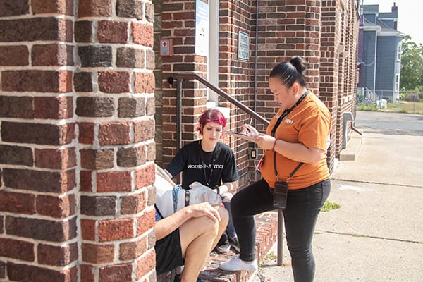 Members of Avivo's Street Outreach Team speak with a person on a staircase.